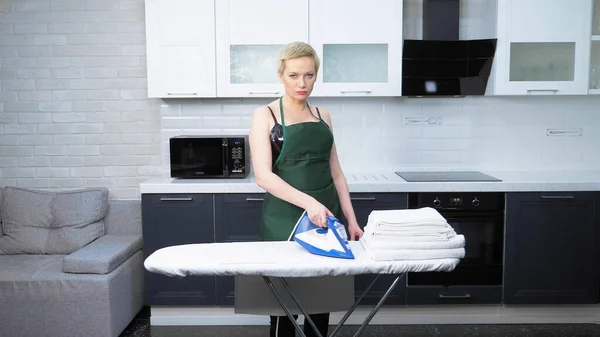 Hermosa mujer en un corsé de cuero y delantal planchas — Foto de Stock