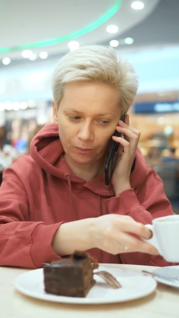 Vertikalt skott. kvinna pratar i telefon sitter på ett café — Stockvideo