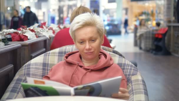 Femme fatiguée au café regarde le menu, en choisissant un plat — Video