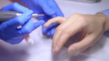 Erkek donanım manikürü. Yakından, lastik eldivenli bir manikürcünün elleri..