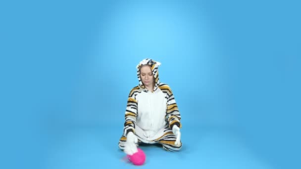 Humor, een vrouw in een kattenkostuum speelt met een bol draad. blauwe achtergrond — Stockvideo