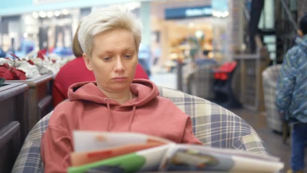 Tired woman in cafe looks at the menu, choosing a dish — Stock Video