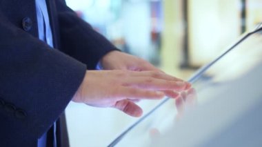 Adam süpermarketteki bilgi masasında dokunmatik ekran kullanıyor