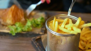 Yakın plan. Adam restoranda pastırmalı sandviç ve patates kızartması yiyor..