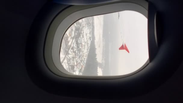 Vertical. la vista desde la ventana del avión, volando sobre la ciudad cubierta de nieve — Vídeos de Stock