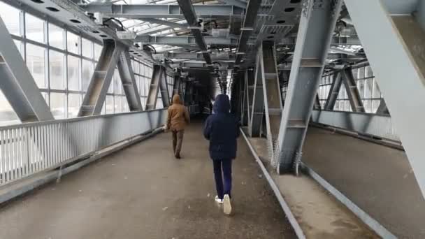 Ένας μοναχικός άντρας με χειμωνιάτικο μπουφάν περπατά μέσα από μια μεταλλική διάβαση πεζών. — Αρχείο Βίντεο