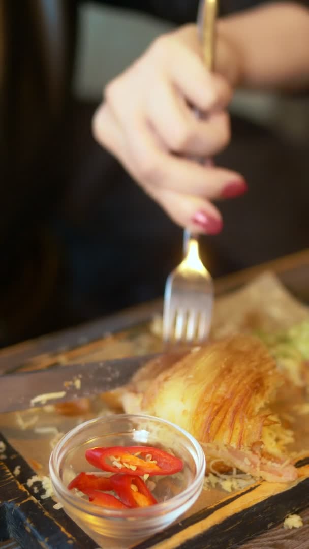 Een close-up. man die een croissant met spek en koffie eet in een café — Stockvideo