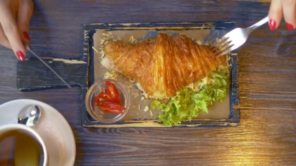 Primer plano. hombre comiendo un croissant con tocino y café en un café — Vídeos de Stock