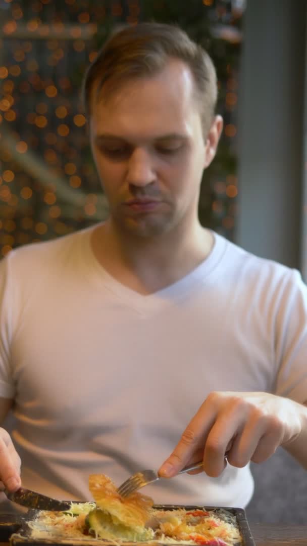 Een close-up. Een man die een croissant met spek en koffie eet in een café. verticaal schot — Stockvideo