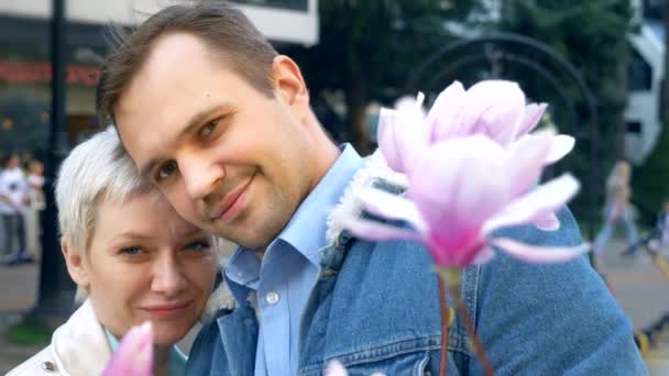 Hermosa pareja enamorada, hombre y mujer entre las flores de la Magnolia rosa — Vídeos de Stock