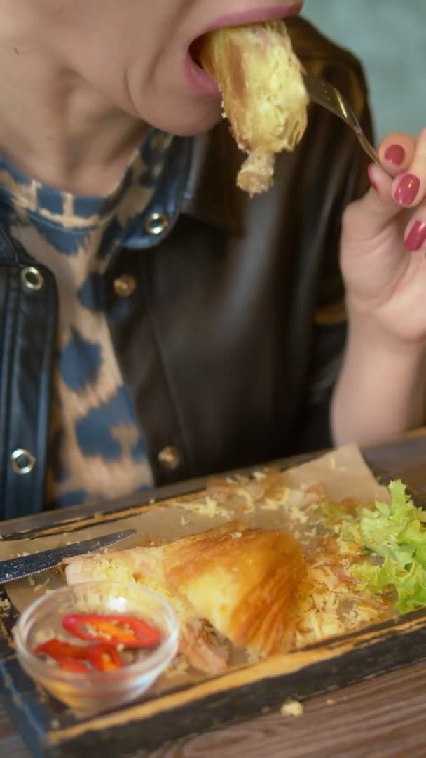 Primer plano. mujer comiendo un croissant con tocino y café en un café — Vídeo de stock