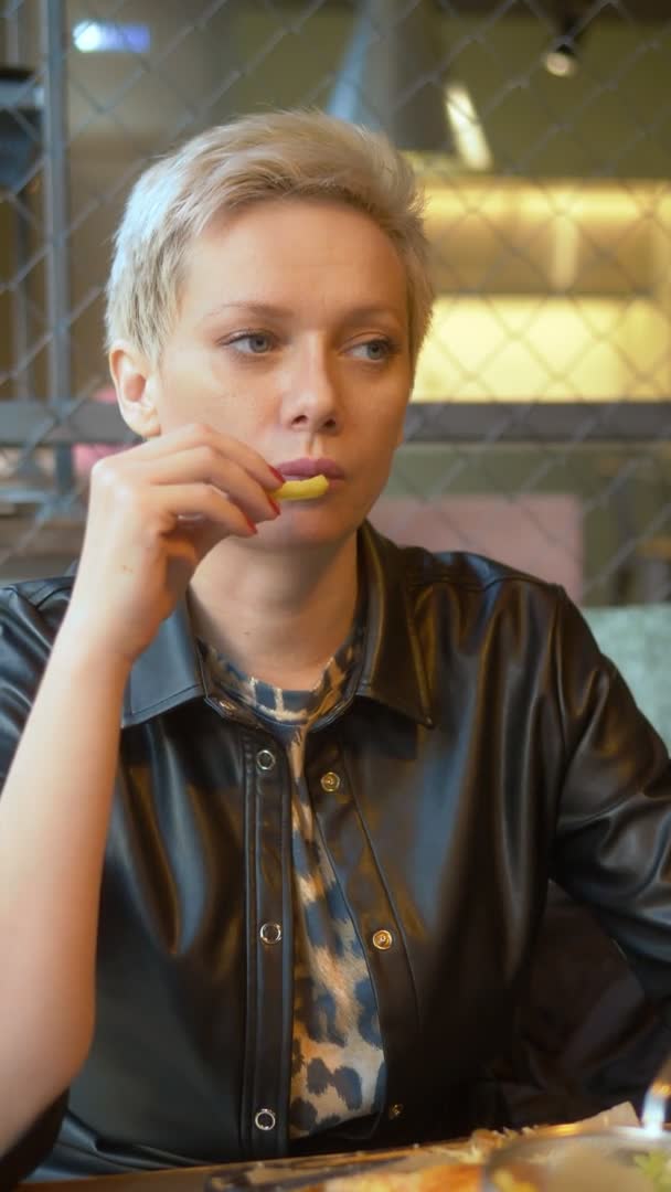 Disparo vertical. mujer comiendo papas fritas en el restaurante — Vídeos de Stock