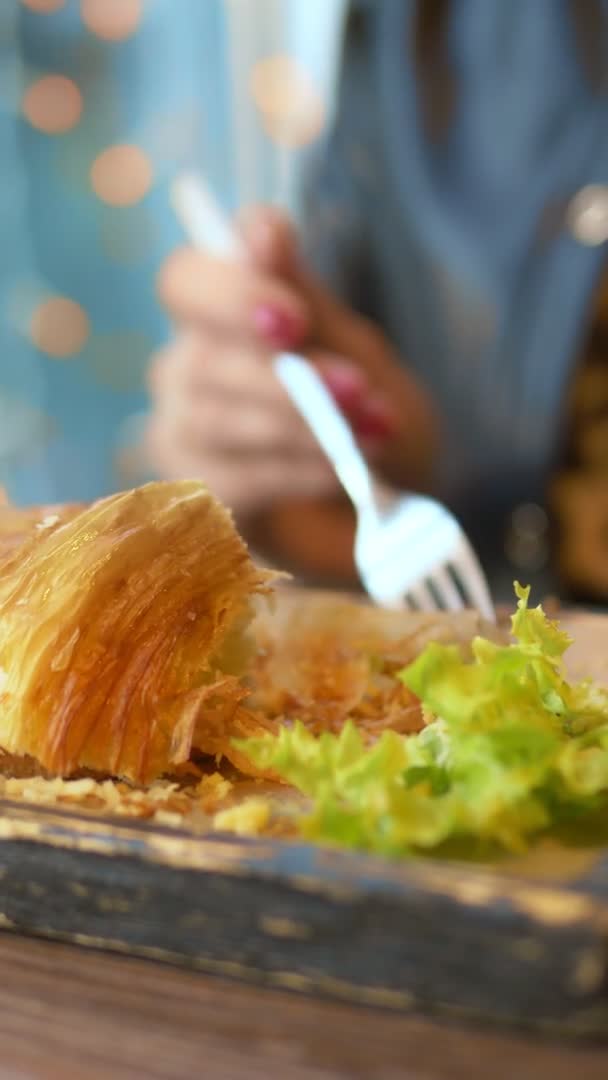 Een close-up. vrouw het eten van een croissant met spek en koffie in een cafe — Stockvideo