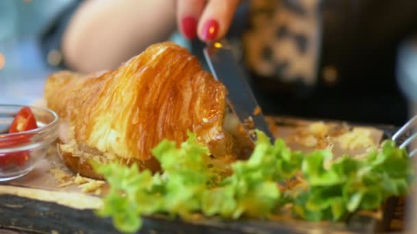 Nahaufnahme. Frau isst Croissant mit Speck und Kaffee in einem Café — Stockvideo