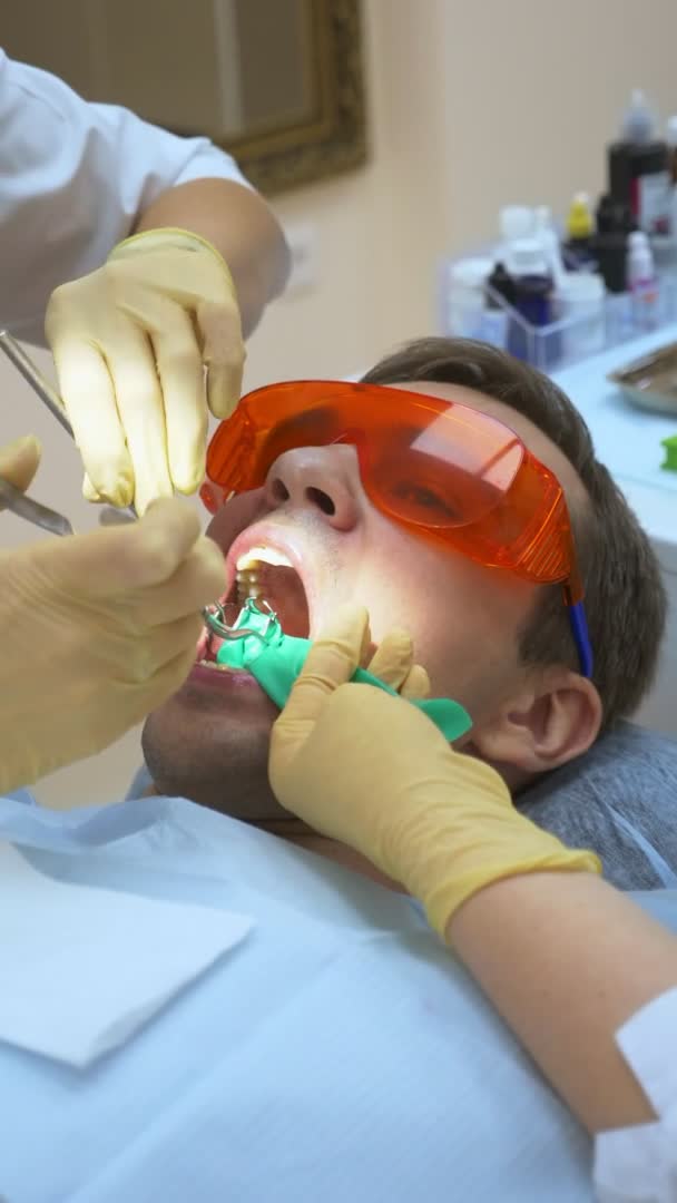 Disparo vertical. Primer plano. dentista trata diente paciente masculino — Vídeos de Stock