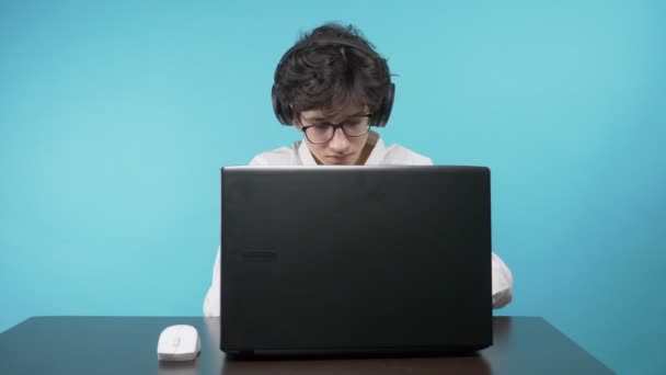 Teenager uses a laptop. blue background. the concept of online education — Stock Video