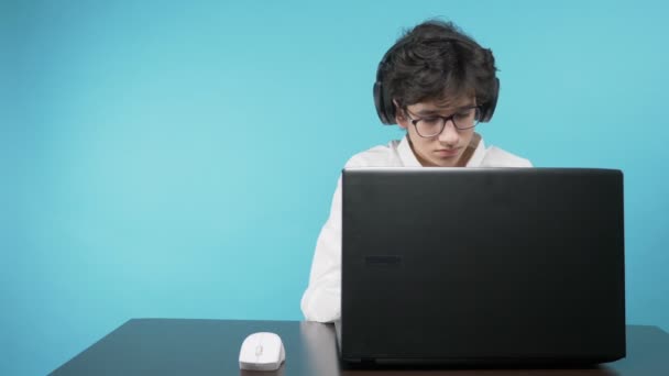 Teenager benutzt Laptop. blauer Hintergrund. das Konzept der Online-Bildung — Stockvideo
