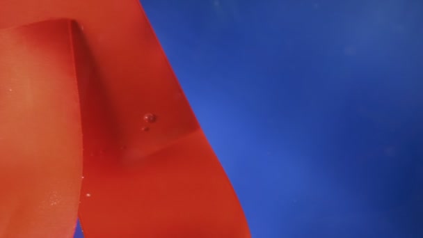 Czerwona wstążka pod wodą. niebieskie tło. przestrzeń kopiowania — Wideo stockowe