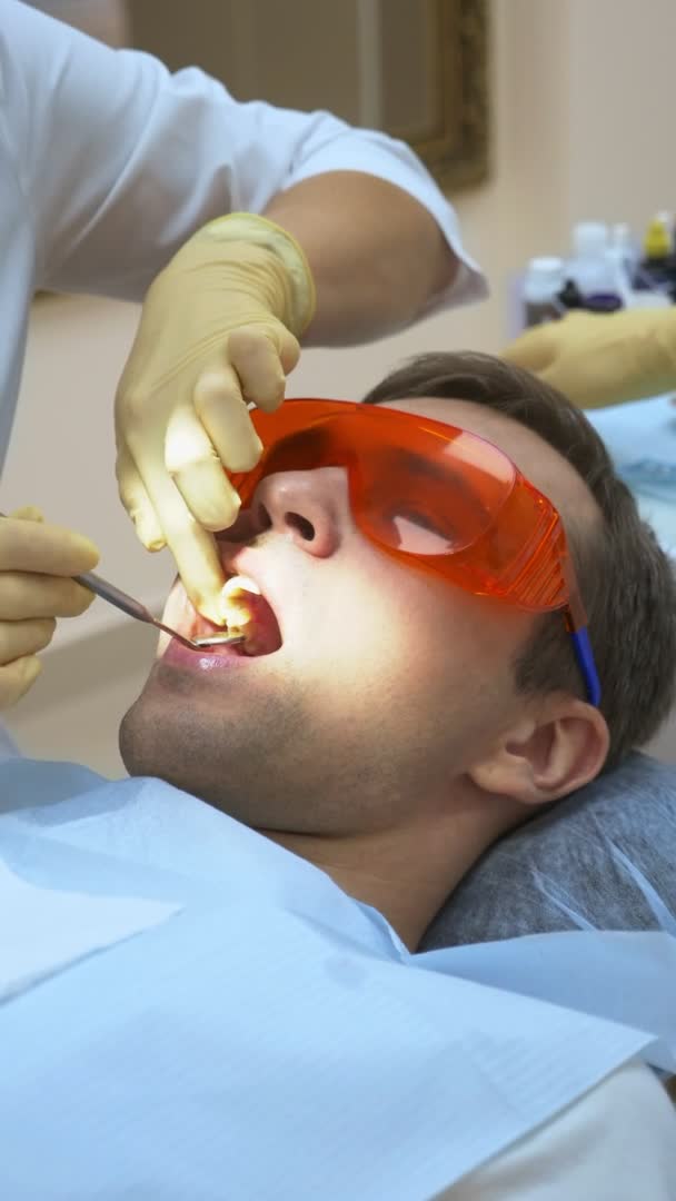 Colpo verticale. il dentista tratta l'uomo bello del dente . — Video Stock