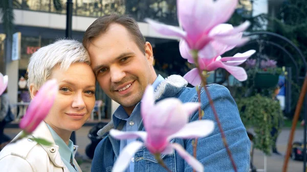 Schönes verliebtes Paar, Mann und Frau inmitten der Blüten der rosa Magnolie — Stockfoto