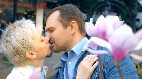 Schönes verliebtes Paar, Mann und Frau inmitten der Blüten der rosa Magnolie — Stockfoto