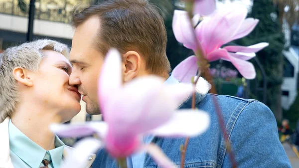 Beautiful couple in love, man and woman among the flowers of the pink Magnolia — Stock Photo, Image