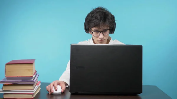 Подросток пользуется ноутбуком. голубой фон. концепция онлайн-образования — стоковое фото
