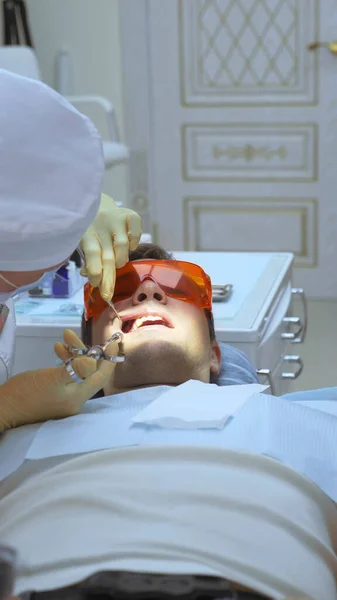 Вертикальний постріл. крупний план. стоматолог лікує зуба пацієнта чоловічої статі — стокове фото