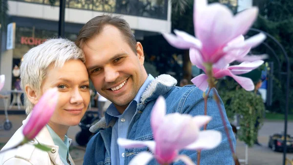 Schönes verliebtes Paar, Mann und Frau küssen sich inmitten der rosa Magnolie — Stockfoto