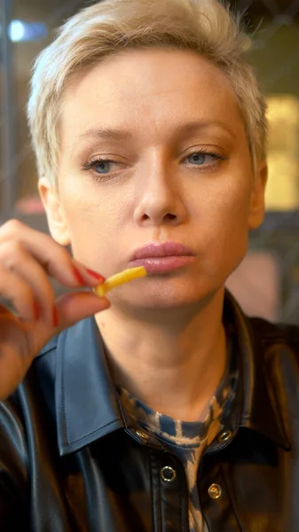 Disparo vertical. mujer comiendo papas fritas en el restaurante — Foto de Stock