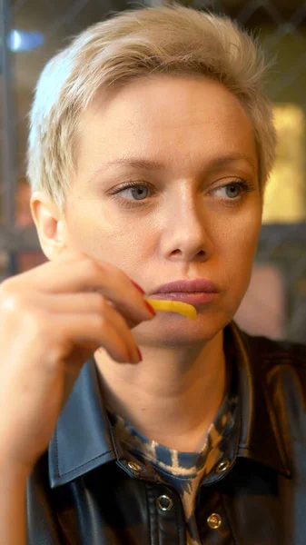 Disparo vertical. mujer comiendo papas fritas en el restaurante — Foto de Stock