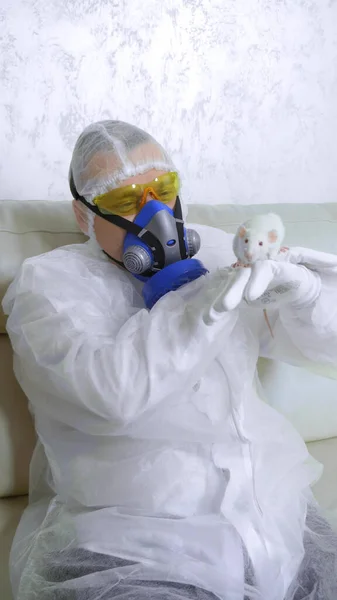 Man in protective suit and respirator looks at a white rat . vertical shot — Stock Photo, Image