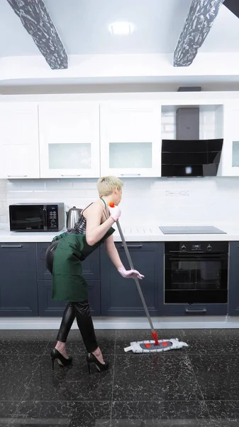 Disparo vertical. una mujer en un corsé de cuero y delantal lava el suelo. humor — Foto de Stock