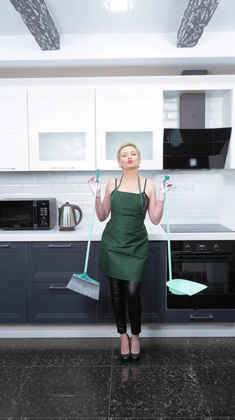 Una imagen vertical. humor. mujer en pantalones de cuero y delantal barriendo el suelo — Foto de Stock