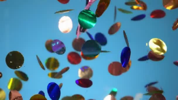 Confetti, masquerade mask and serpentine underwater on a blue background — Stock Video