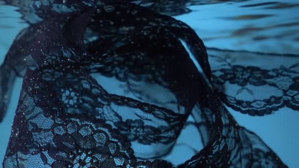 Μαύρη δαντέλα περιστρέφεται κάτω από το νερό σε μπλε φόντο. αντίγραφο χώρου — Αρχείο Βίντεο