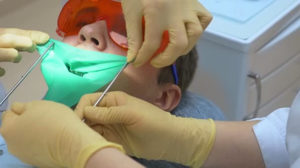 클로즈업. 치과의 사는 치아의 남성 환자를 치료 한다. 커 퍼담 을 사용 함 — 비디오