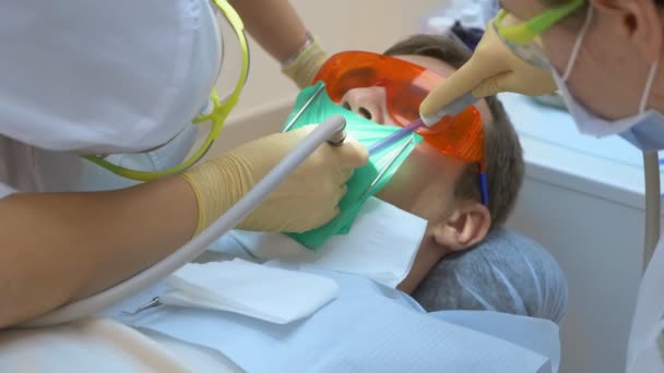 Yakın plan. Diş hekimi erkek hastayı tedavi ediyor. cofferdam kullanarak — Stok video