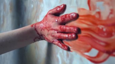 Bir dişi el uzanıyor, duvara tutunuyor, arkasında kan izi bırakıyor.