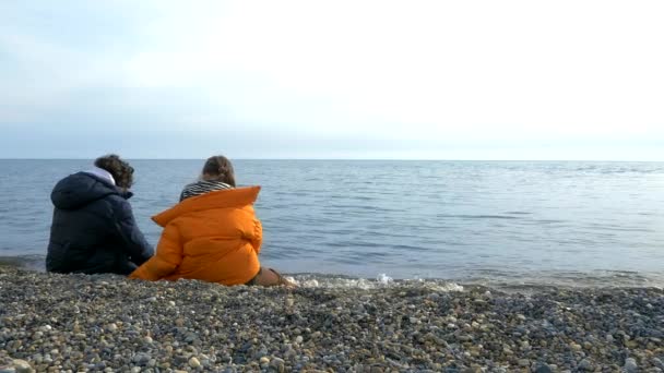 Niños y niñas adolescentes sentados en la caída de la playa, mirando al mar — Vídeos de Stock