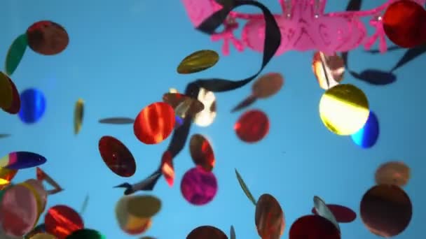Confetti, masquerade mask and serpentine underwater on a blue background — Stock Video