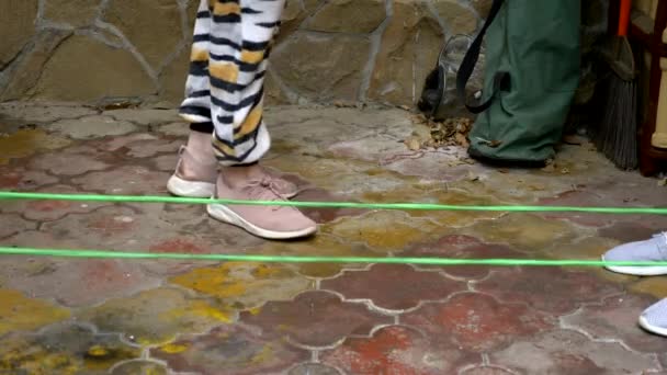 Närbild av fötter hoppar över elastiskt band på bakgården. aktiva spel — Stockvideo