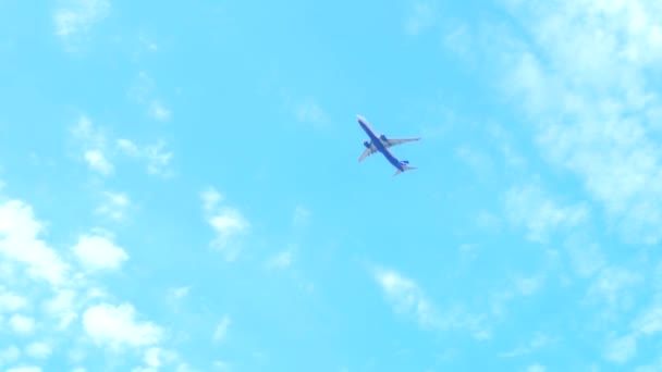 Widok od dołu do góry. Samolot leci na niebieskim niebie z chmurami. — Wideo stockowe