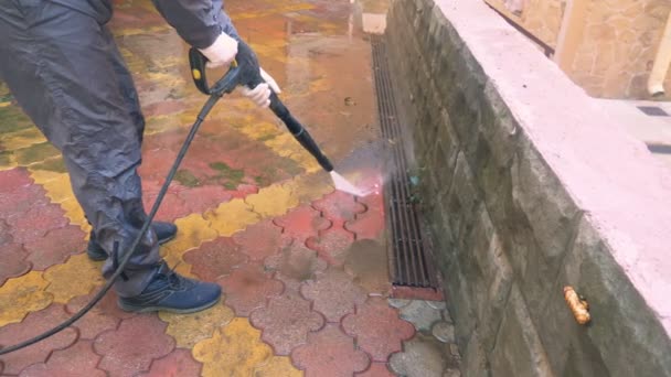 A man cleans the tile on the sidewalk from the build up of dirt. — Stock Video