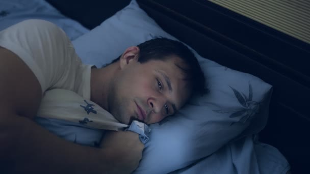 Κοντινό πλάνο. νεαρός άνδρας ξαπλώνει στο κρεβάτι με ανοιχτά μάτια, υποφέρει από αϋπνία. — Αρχείο Βίντεο