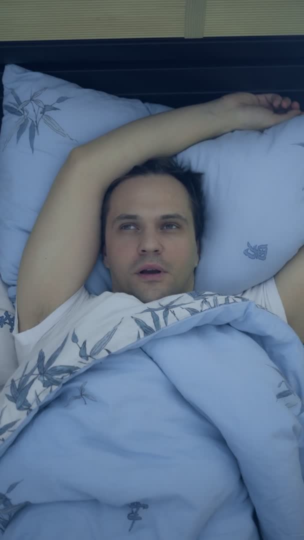Pohled shora. detailní záběr. mladý muž v posteli trpí nespavostí. svisle — Stock video