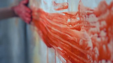 Bir dişi el uzanıyor, duvara tutunuyor, arkasında kan izi bırakıyor.