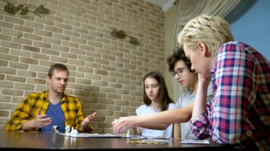 Aile anne, baba, genç kız ve oğlan evde masa oyunu oynuyorlar..