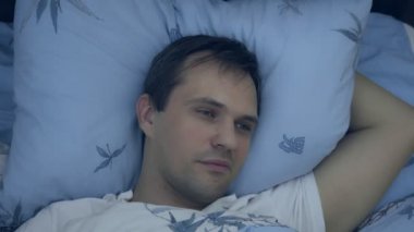 Yakın plan. Uykusuzluk çeken, gözleri açık genç bir adam..