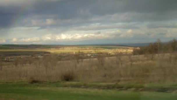 La vue depuis la fenêtre latérale de la voiture dans les champs et les buissons sur les collines — Video